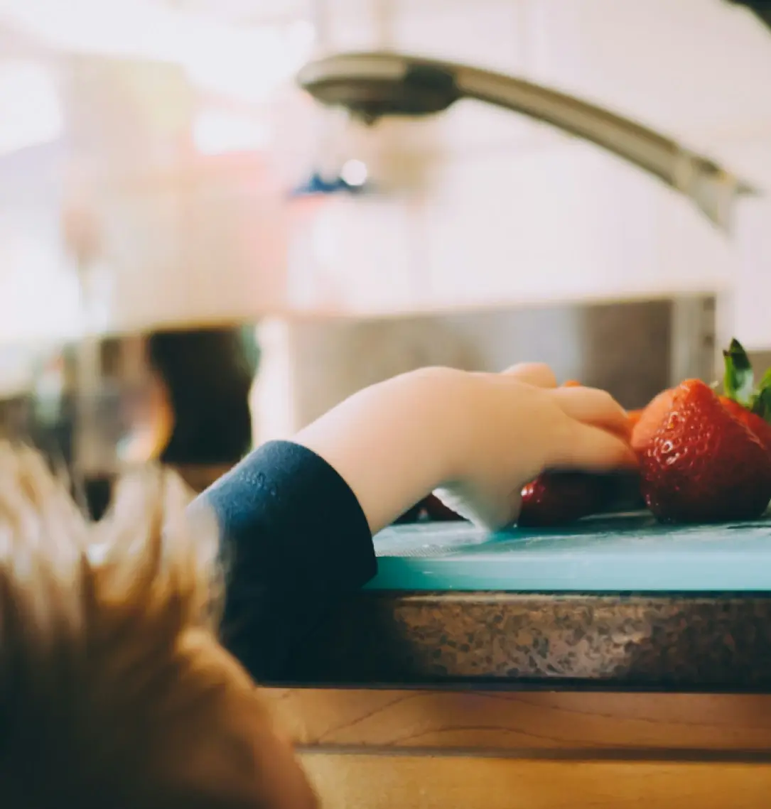 Litet barn tar jordgubbe från köksdisk 